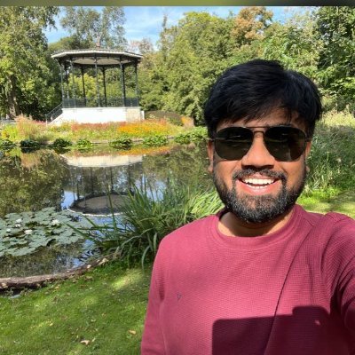 Bulia, smiling in sunglasses by a pond